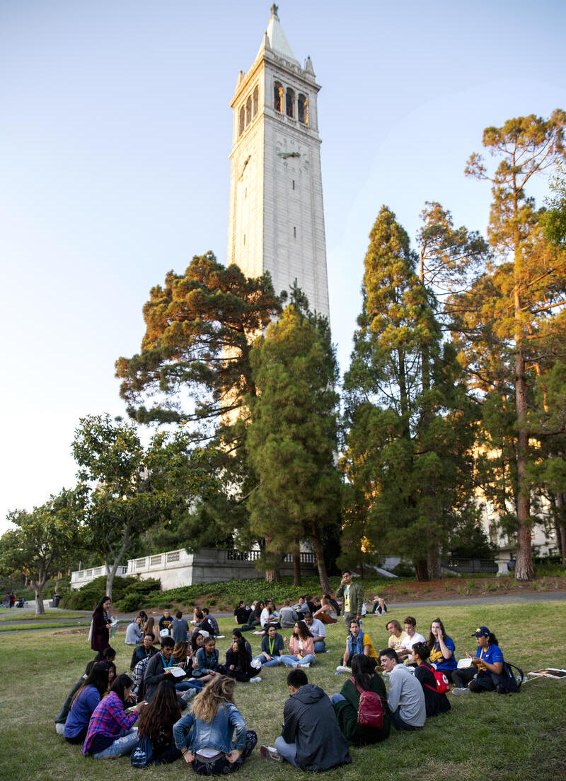 Group of students sitting in a circle in front of Bell tower