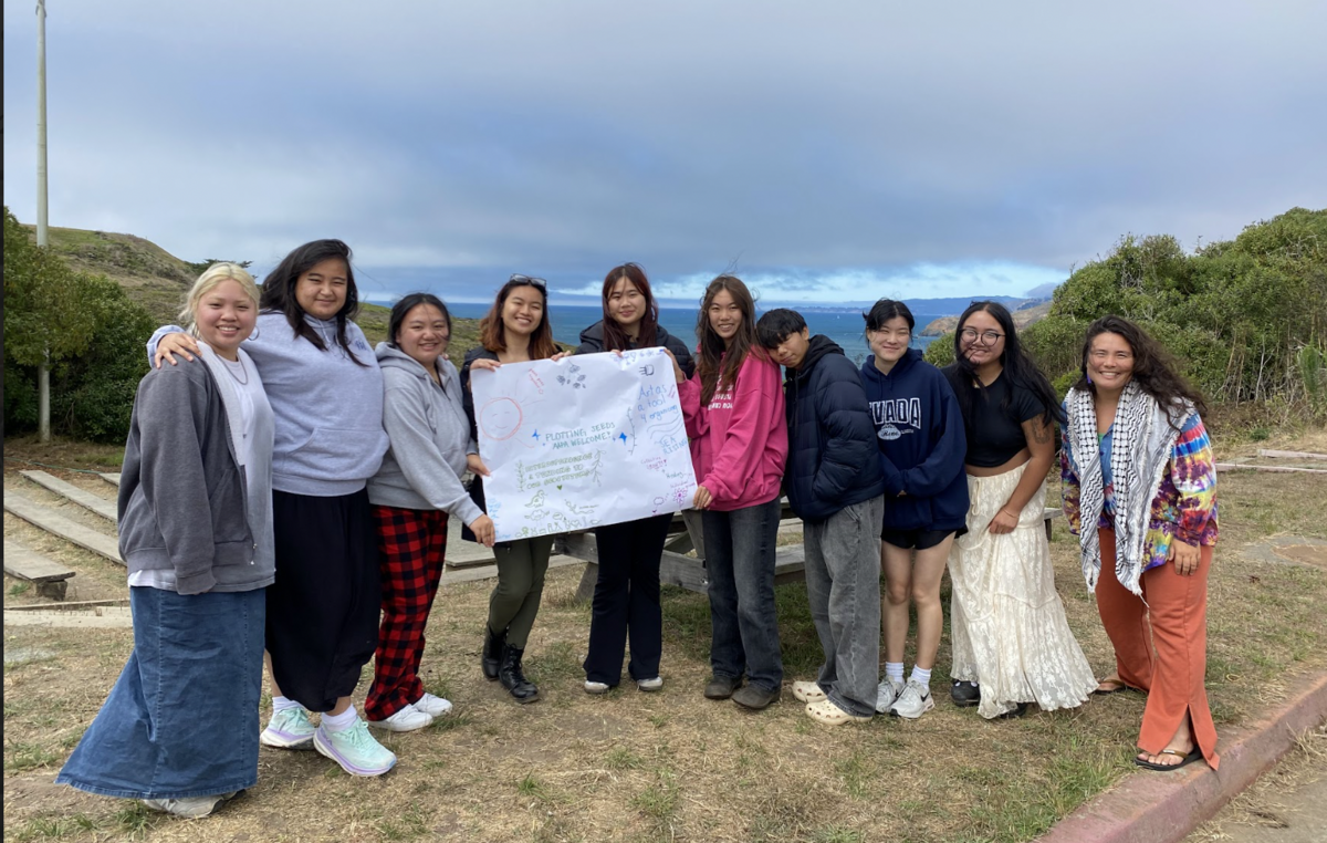 Group photo of AAPA interns standing with ocean view behind them and holding a small banner