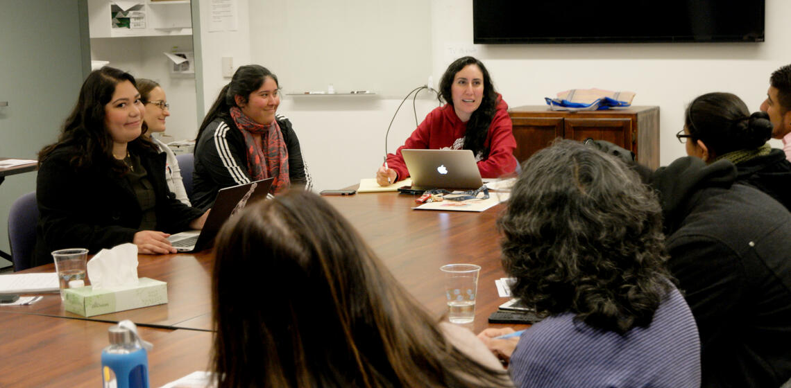 Students and staff talking sitting in a conference room.