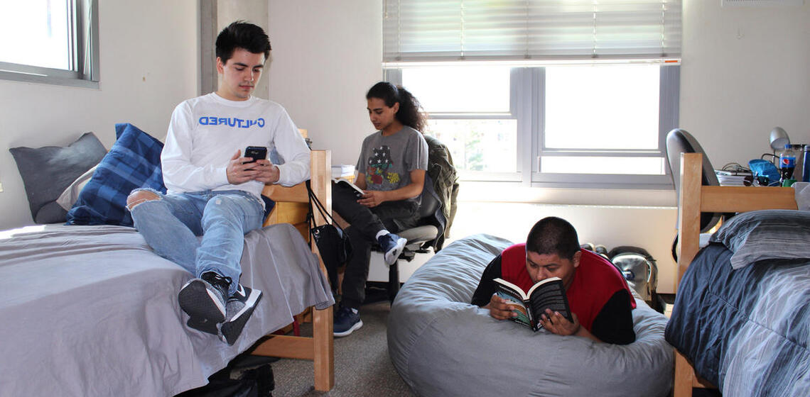Group of three boys lounging around their dorm room