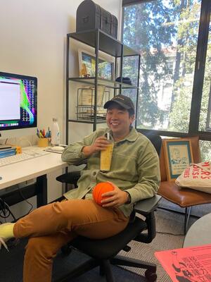 A photo of Eunice sitting at her desk drinking boba and smiling